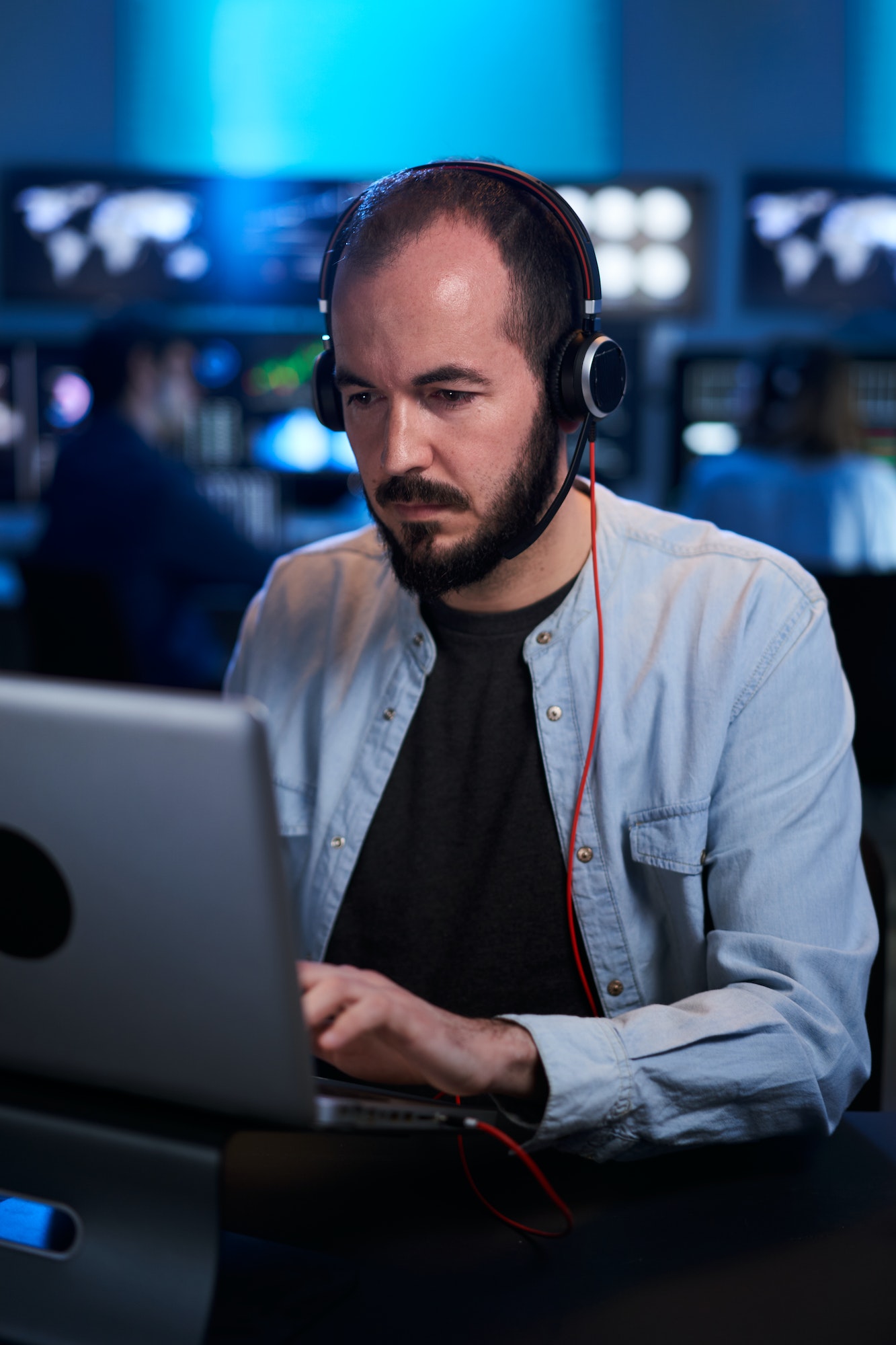 Vertical photo of a stockbrokers having a conversation in a dark office with display screens.